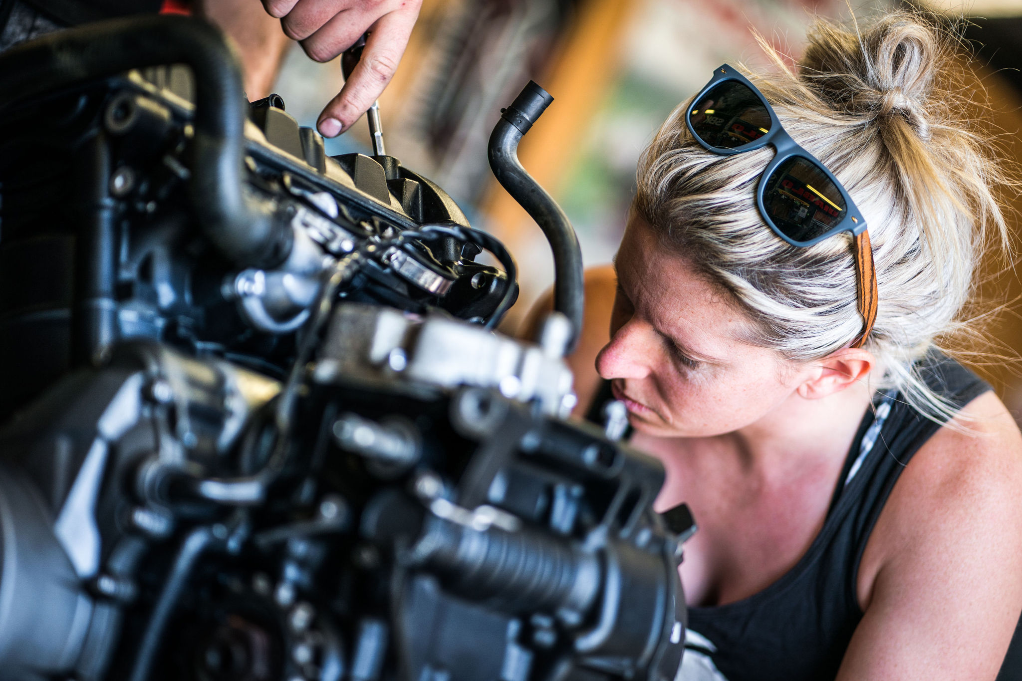 Technician servicing a motorcycle in a workshop.